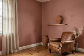 Salon décoré avec une peinture murale rose poudré associée à des tons beige, terracotta et bois naturel